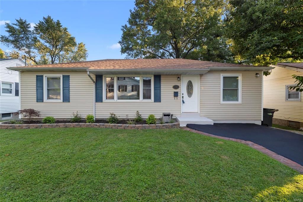 A house with a large lawn and a driveway in front of it.