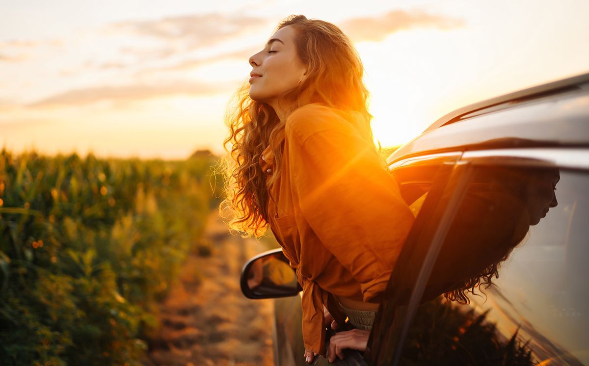 A woman is sitting in a car with her eyes closed.