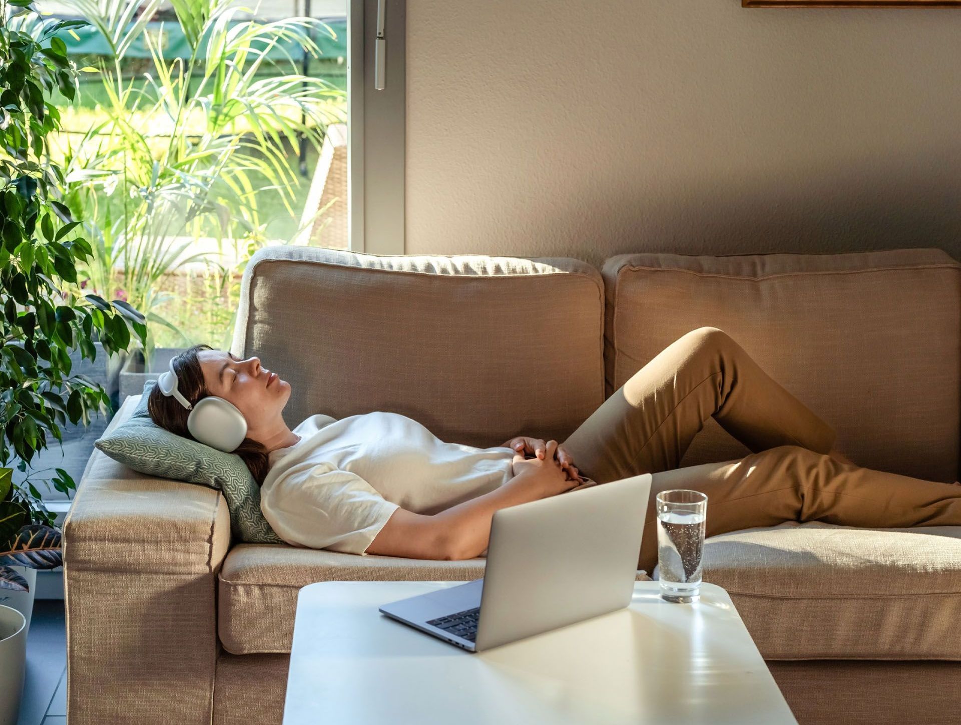 A woman is laying on a couch wearing headphones and listening to therapy.