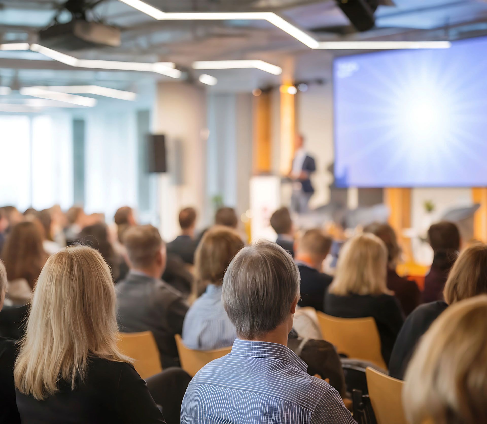 A group of people are sitting in a conference room watching a presentation.
