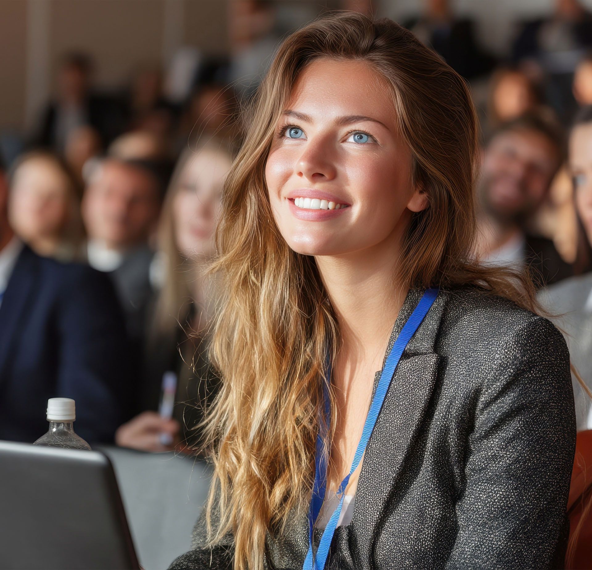 A woman is smiling while sitting in front of a laptop