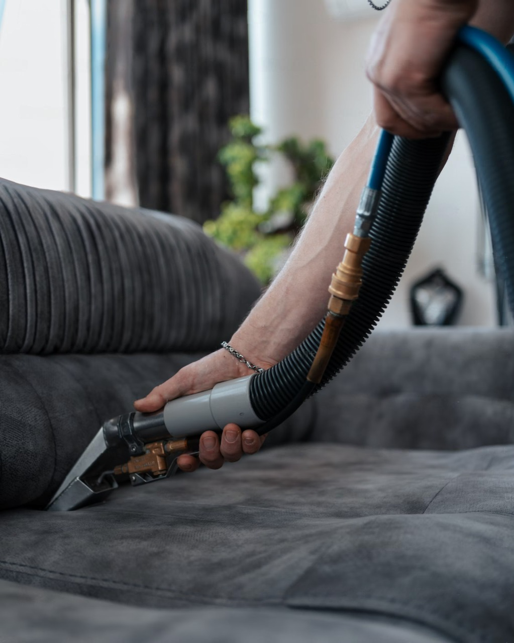 A man is cleaning a carpet with a vacuum cleaner in a living room.