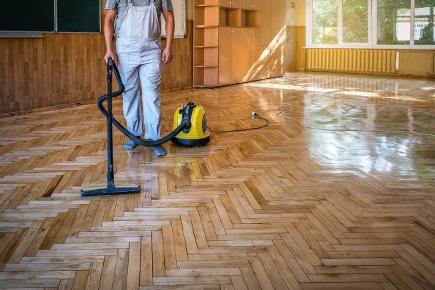 A man in a protective suit is spraying a floor in an office.