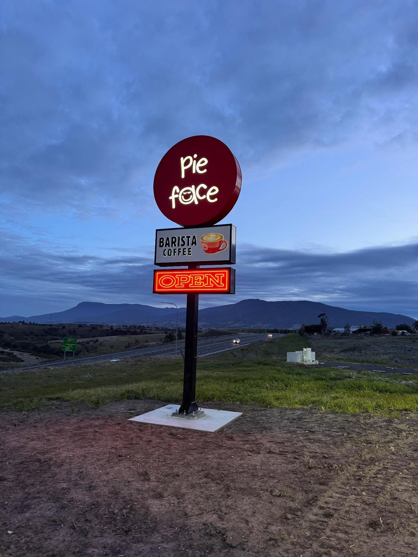 Empty storage unit with metal roof and walls, three lights, concrete floor, black wall on the left, white wall on the right.