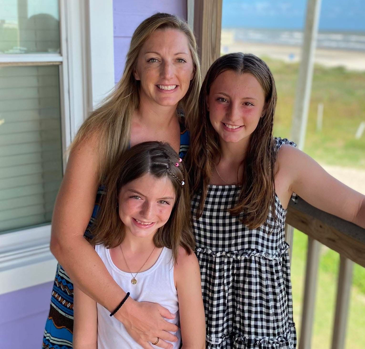A woman and two girls are posing for a picture on a balcony.