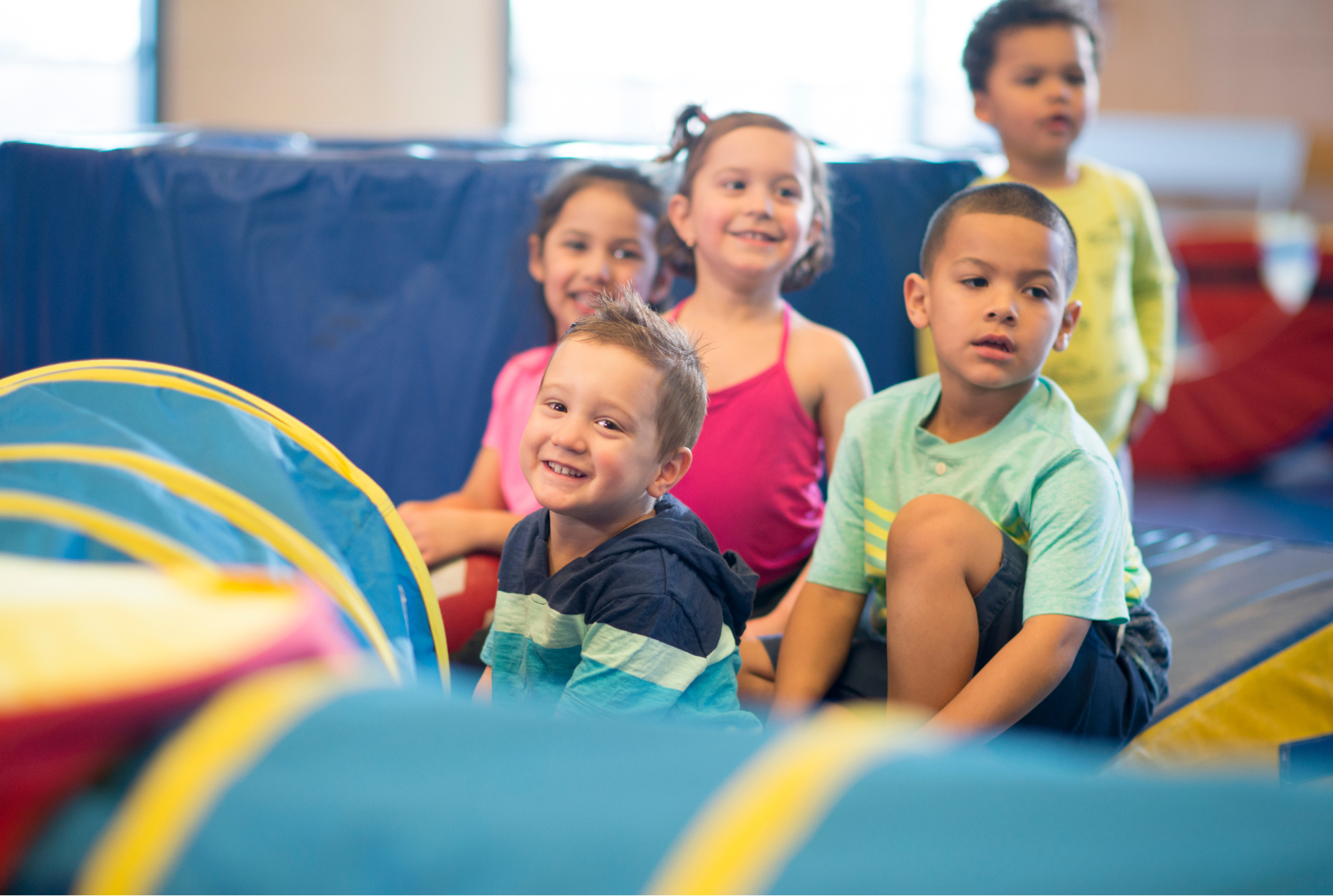 A group of young children are sitting in a play tunnel.