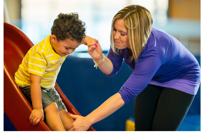 A little girl is standing on a balance beam in a gym.