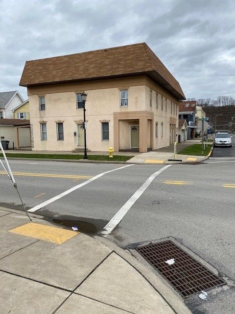 A building with a brown roof sits on the corner of a street