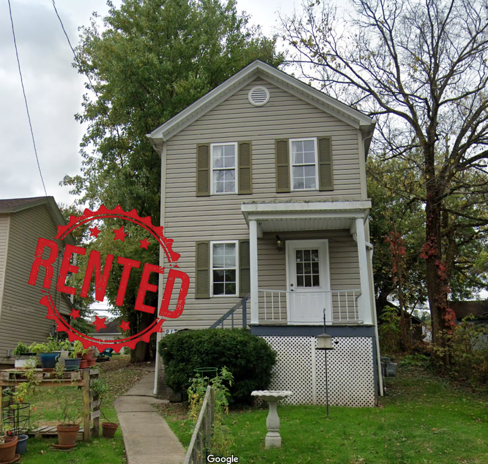 A person is putting coins into a stack of coins next to a model house.