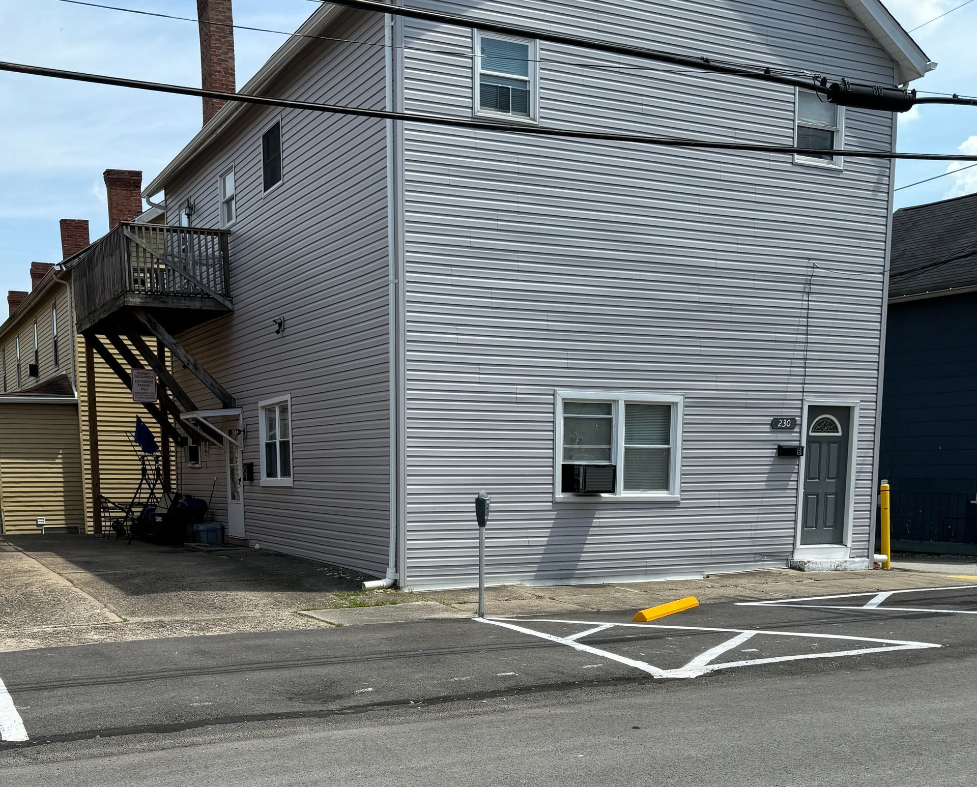 A gray building with a red door is sitting on the corner of a street.
