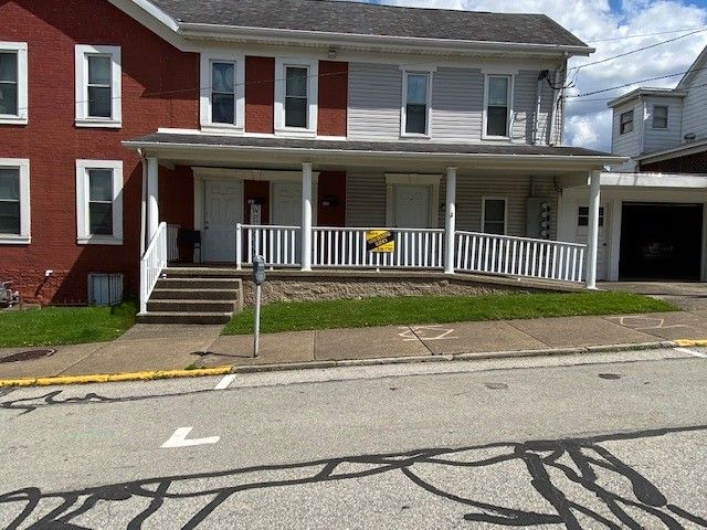 A red and white house with a yellow sign on the front porch.