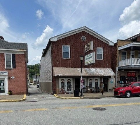 A gray building with a red door is sitting on the corner of a street.