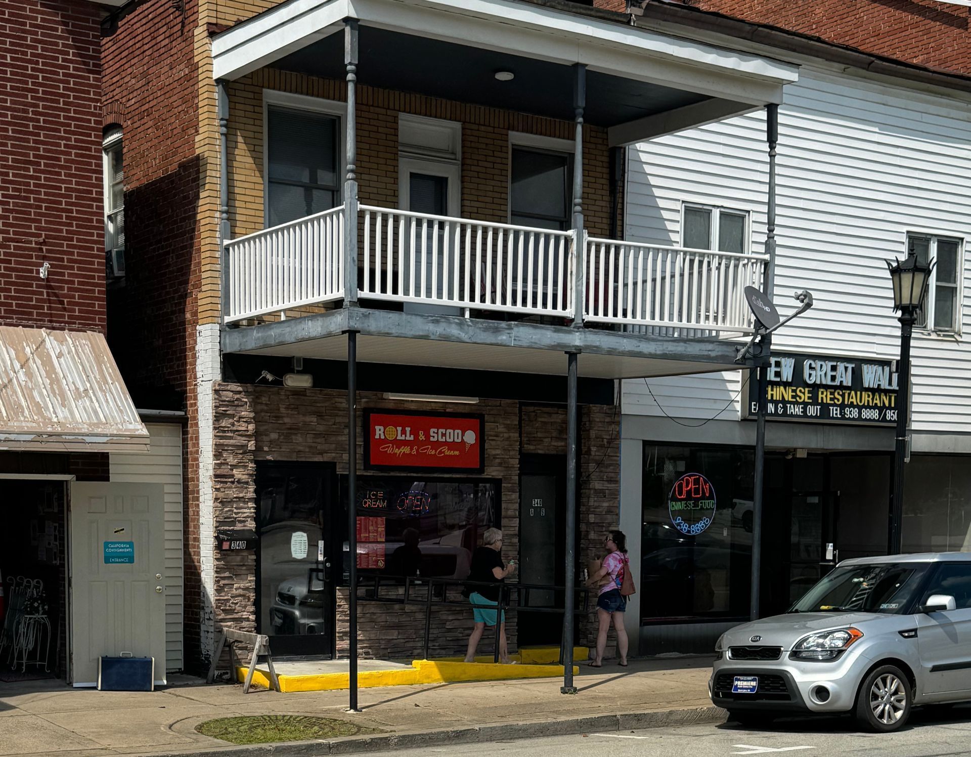 A car is parked in front of a building with a balcony.