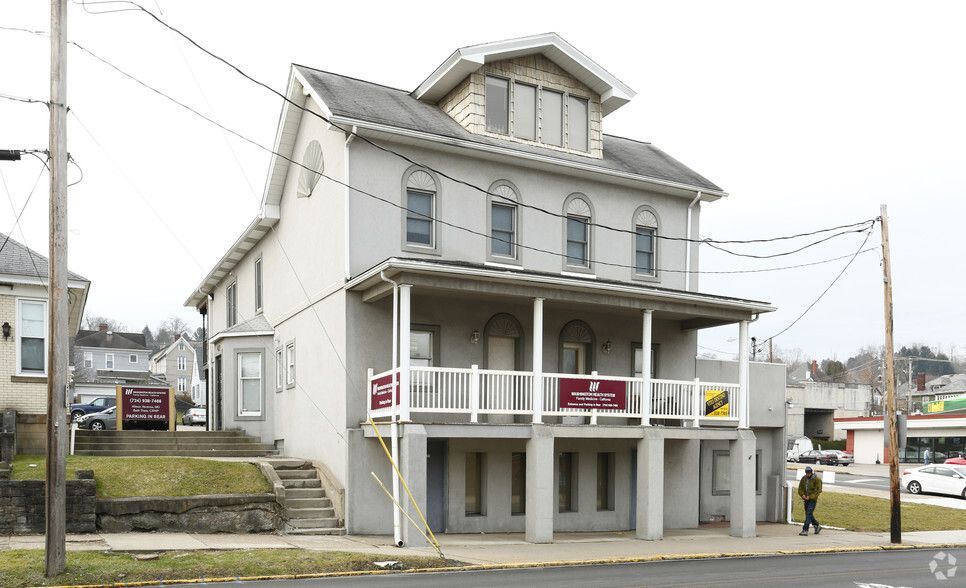A gray building with a red door is sitting on the corner of a street.