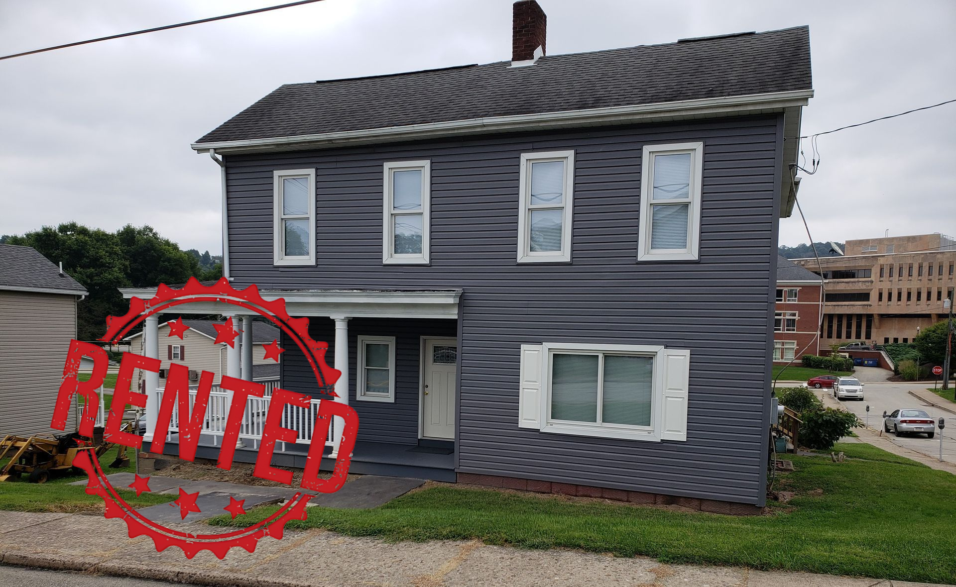 A gray building with a red door is sitting on the corner of a street.