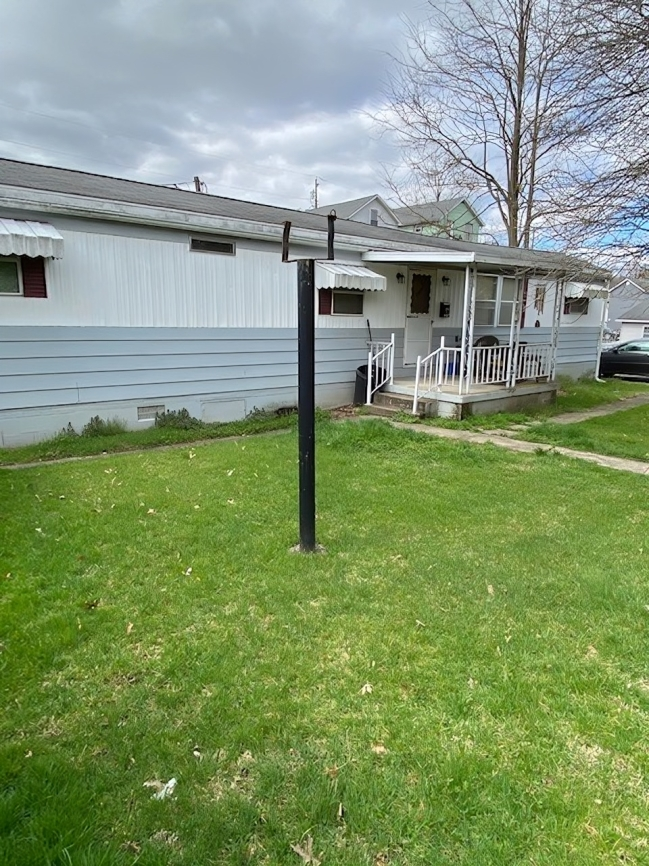 A house with a porch and a lawn in front of it.