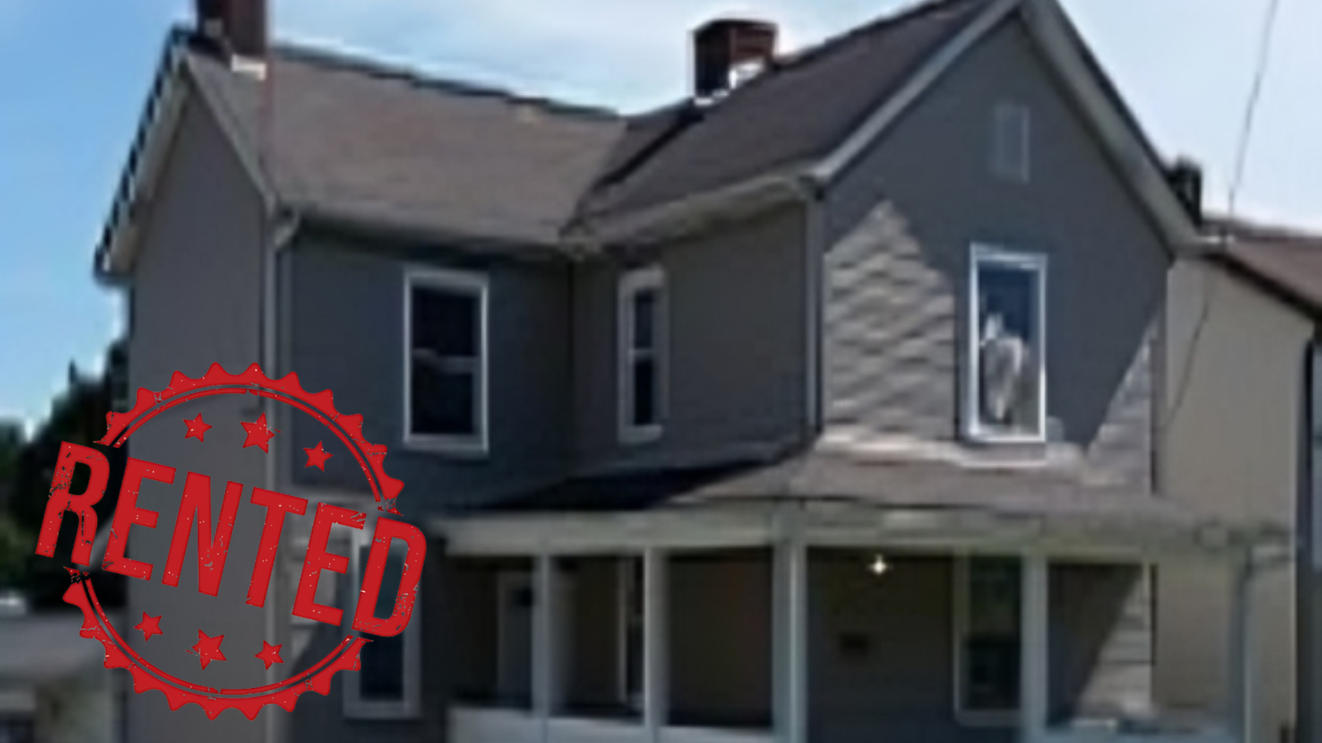 A large house with a porch is sitting on the corner of a street.