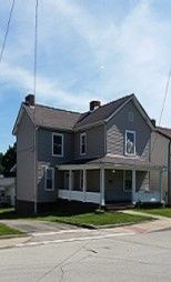 A large house with a large porch is decorated for christmas.
