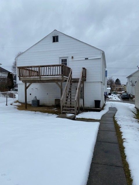 A white house with a deck and stairs in the snow
