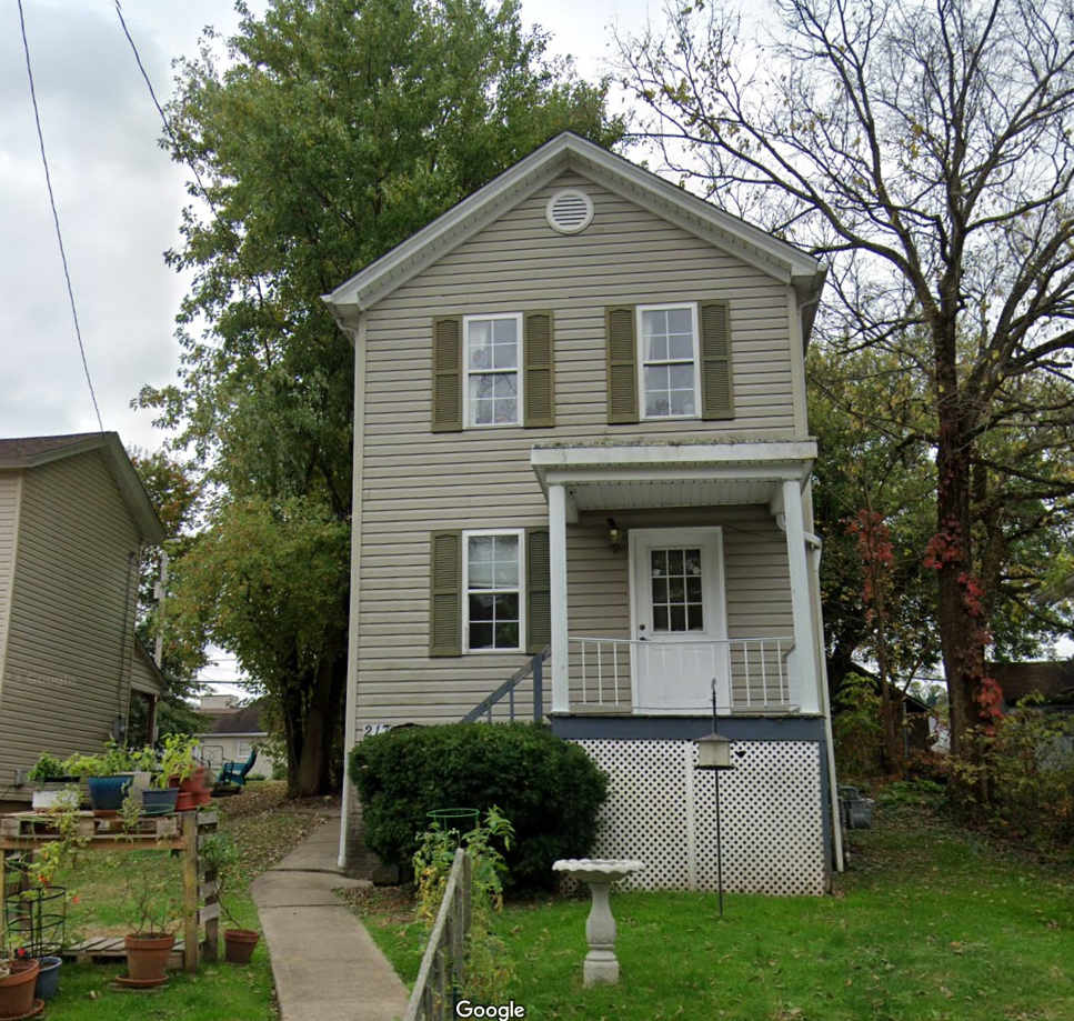A person is putting coins into a stack of coins next to a model house.