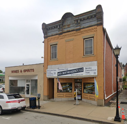 A gray building with a red door is sitting on the corner of a street.