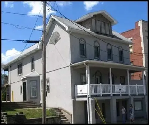 A gray building with a red door is sitting on the corner of a street.