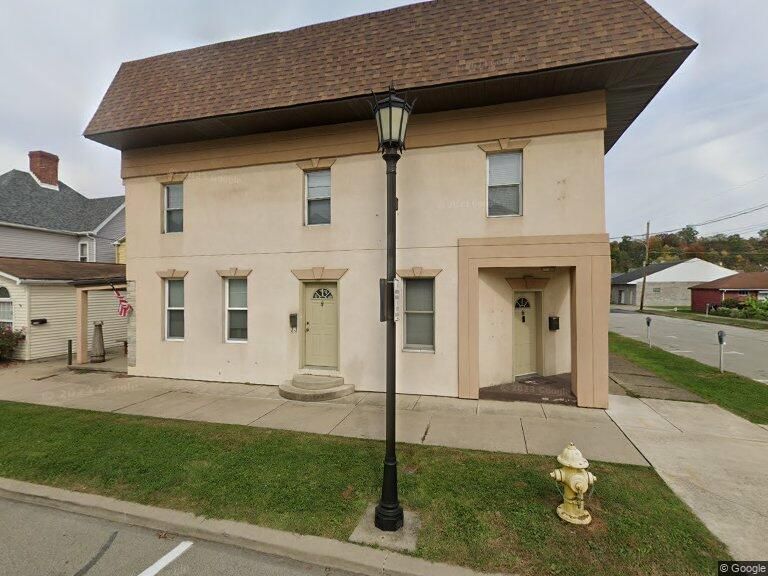A gray building with a red door is sitting on the corner of a street.