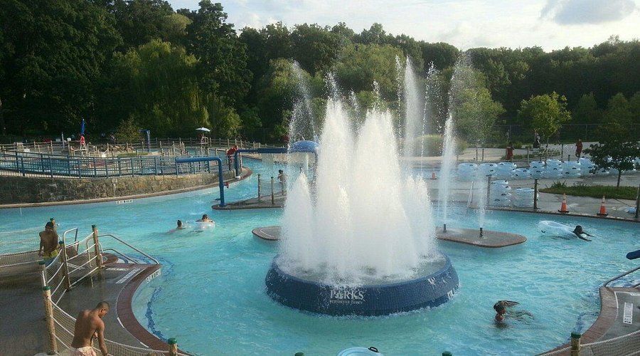 People are swimming in a pool with a fountain in the middle.