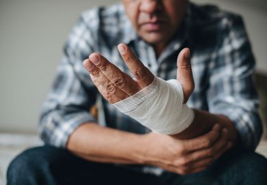 A man with a bandaged hand is sitting on a couch.