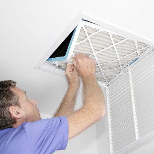 A man is installing a filter in an air vent.