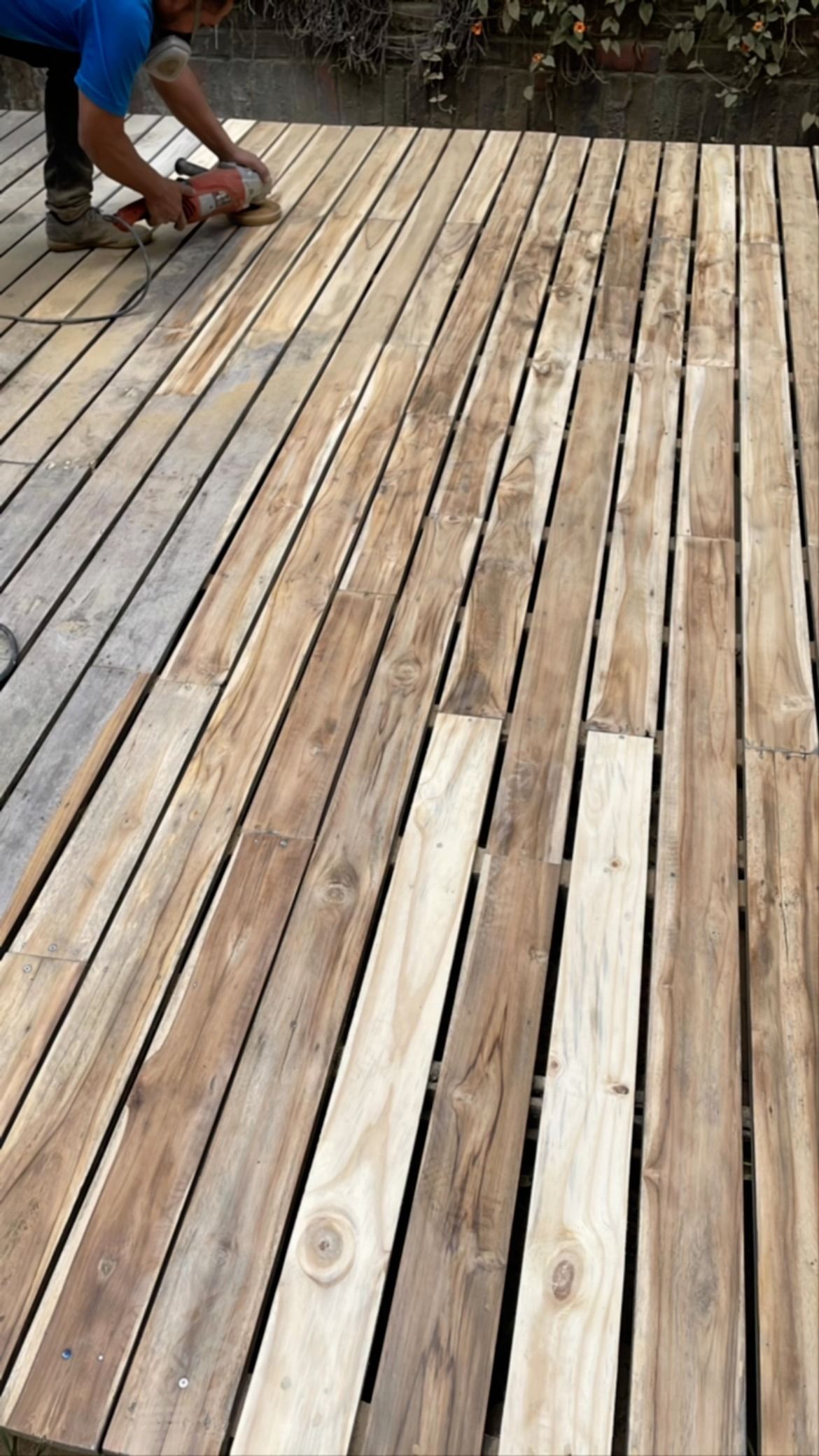 Persona lijando una terraza de madera al aire libre.