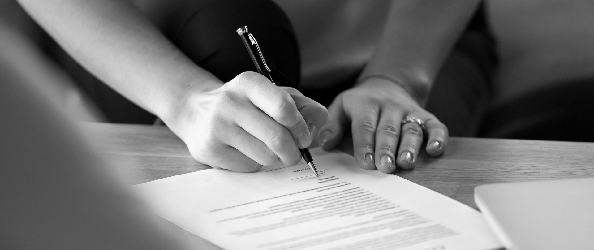 A person is writing on a piece of paper with a pen.