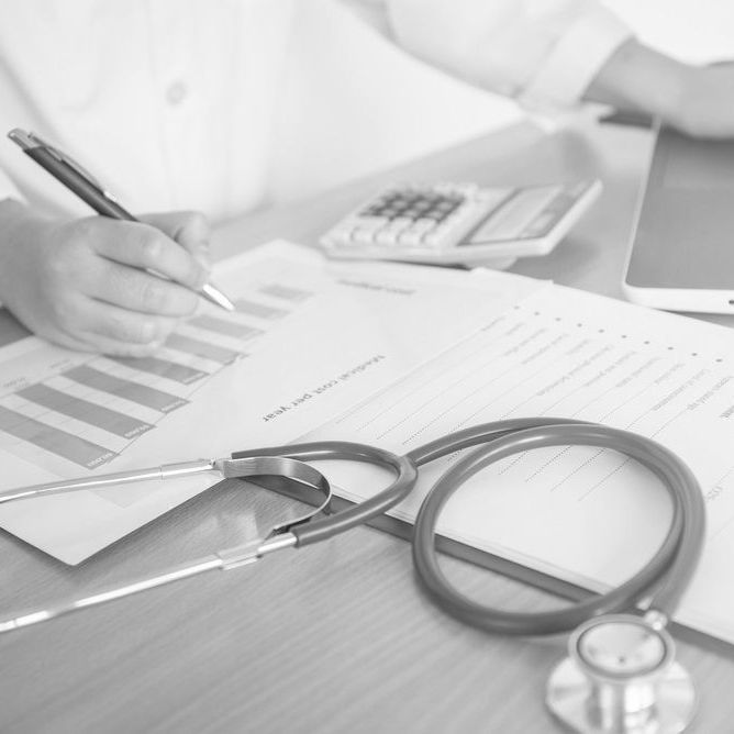 A person is writing on a piece of paper next to a stethoscope.