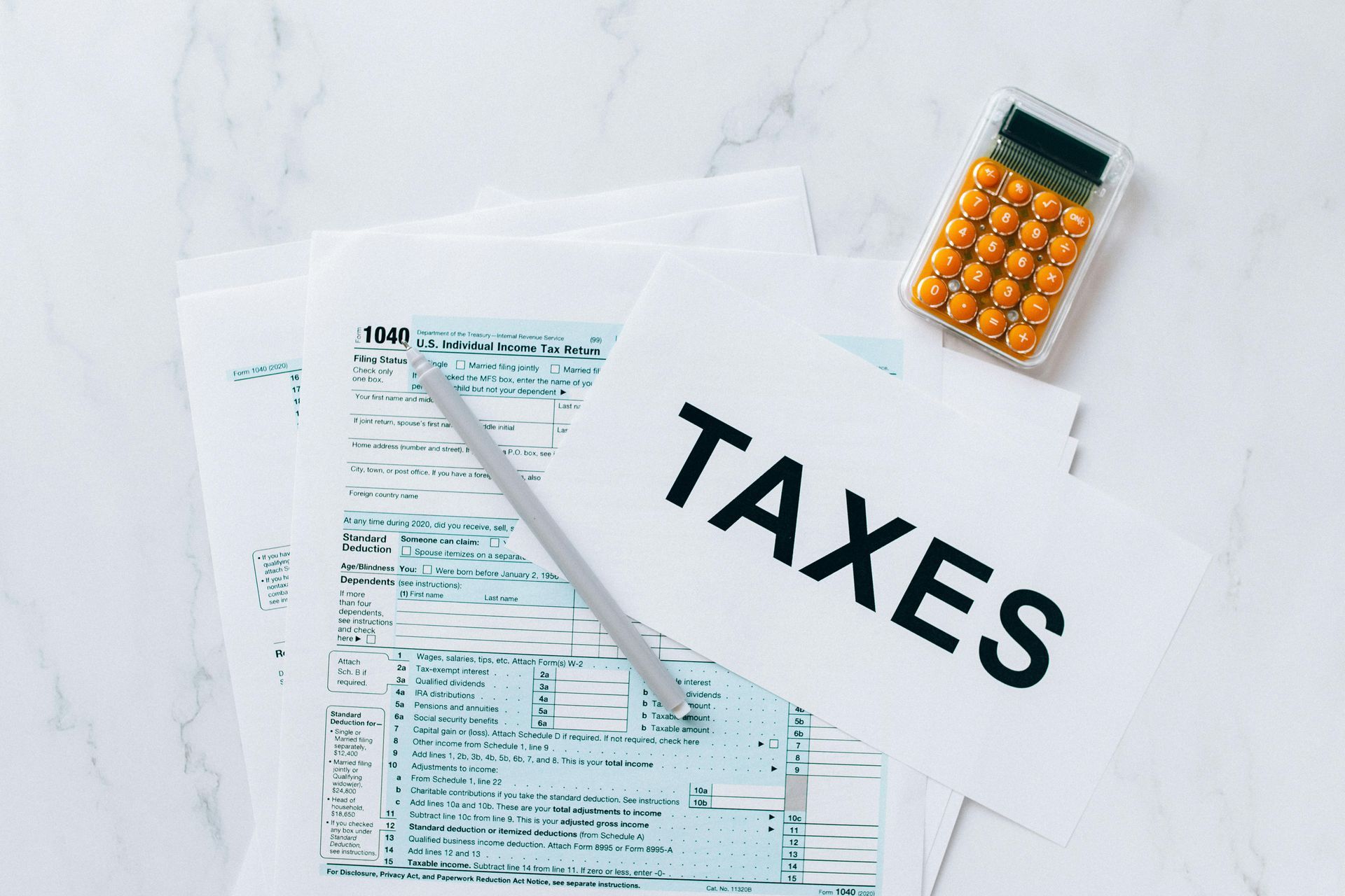 A calculator is sitting on top of a pile of tax forms.