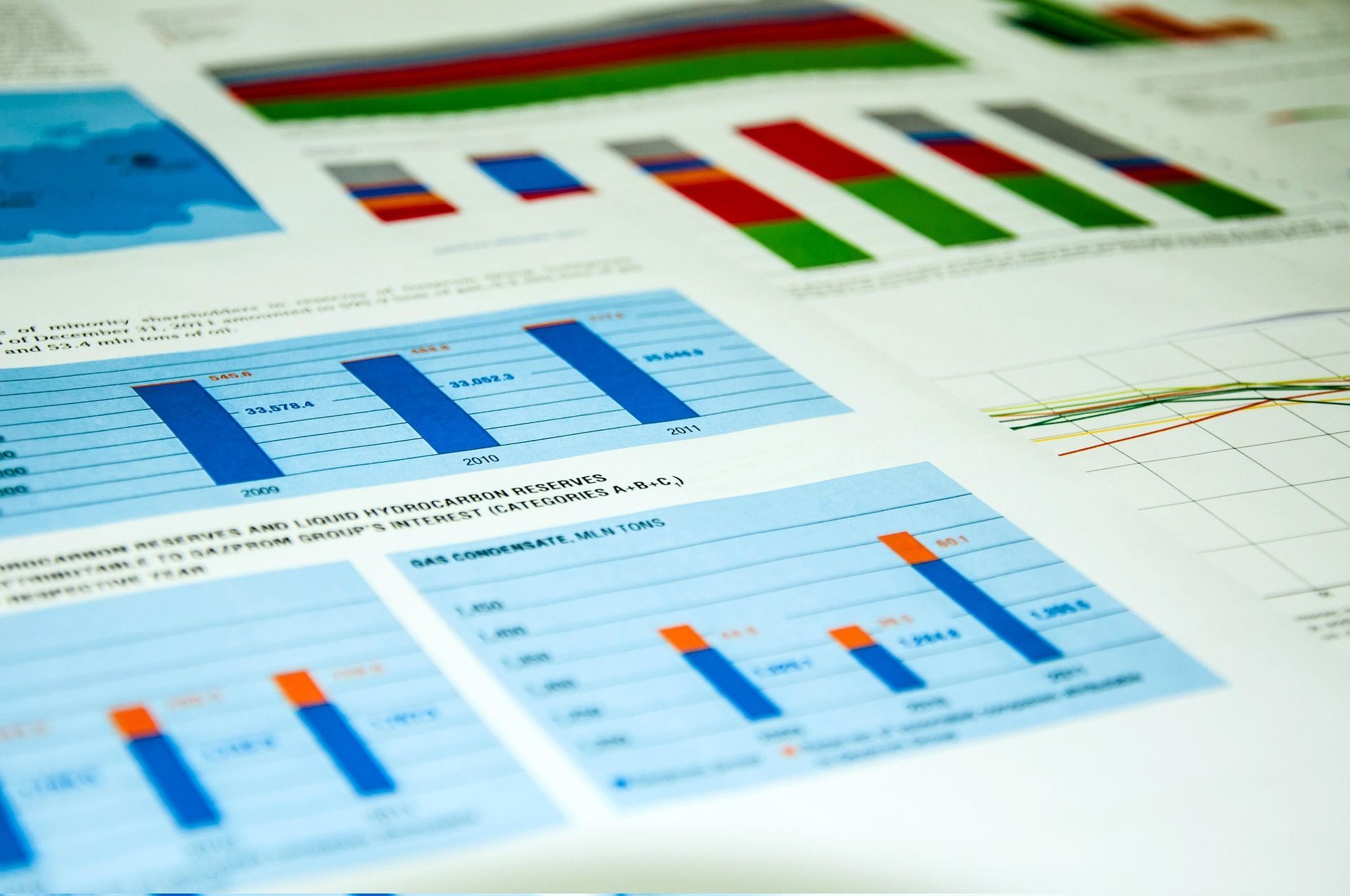 Charts and graphs in blue, green, red, and orange on white paper, displaying statistical data.
