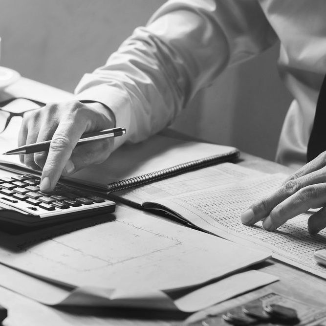 A black and white photo of a person using a calculator