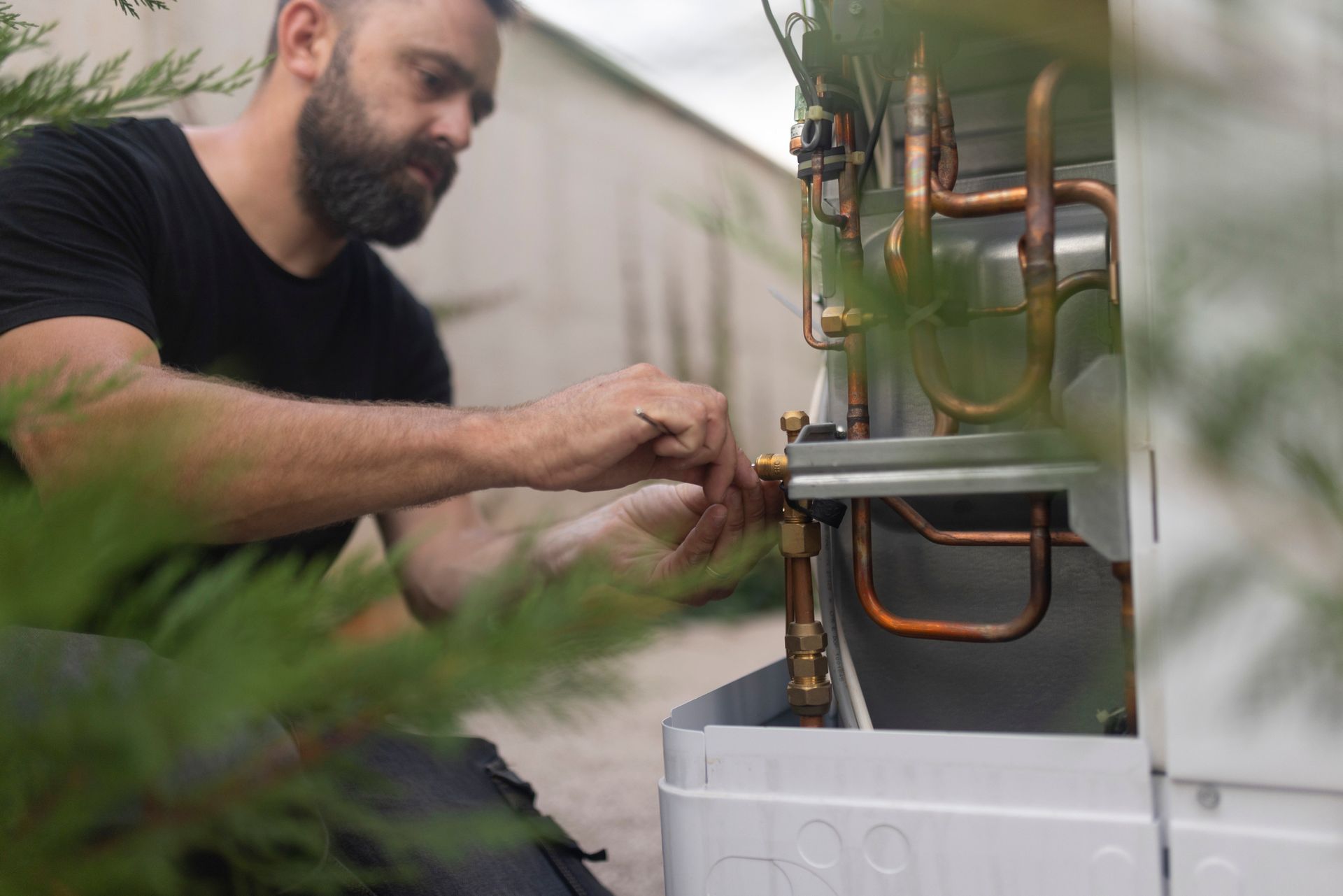 A man with a beard is working on a heating system.
