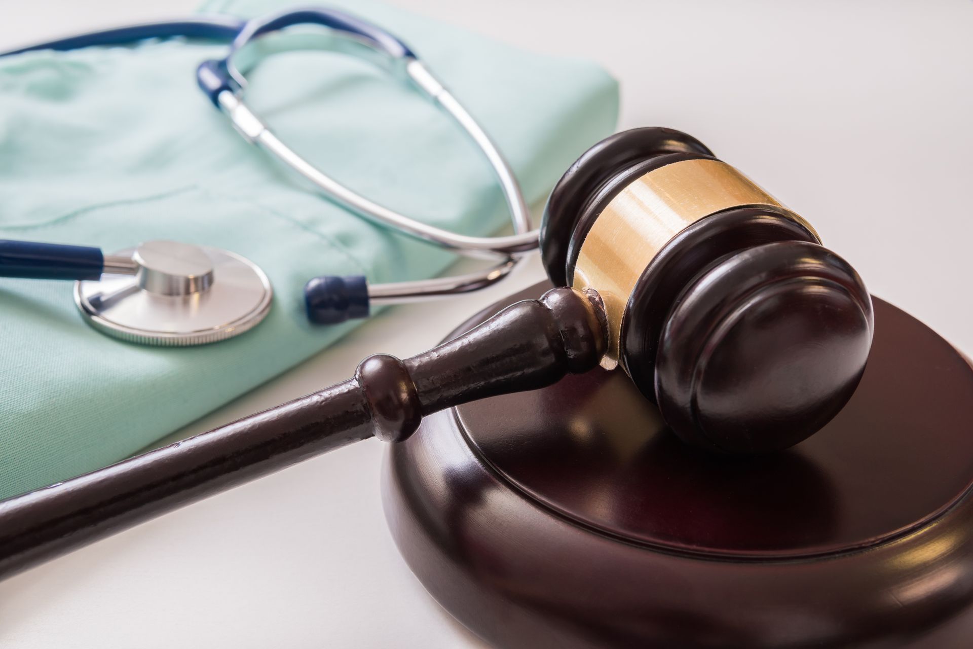 A judge 's gavel is sitting next to a stethoscope and a nurse 's scrub.
