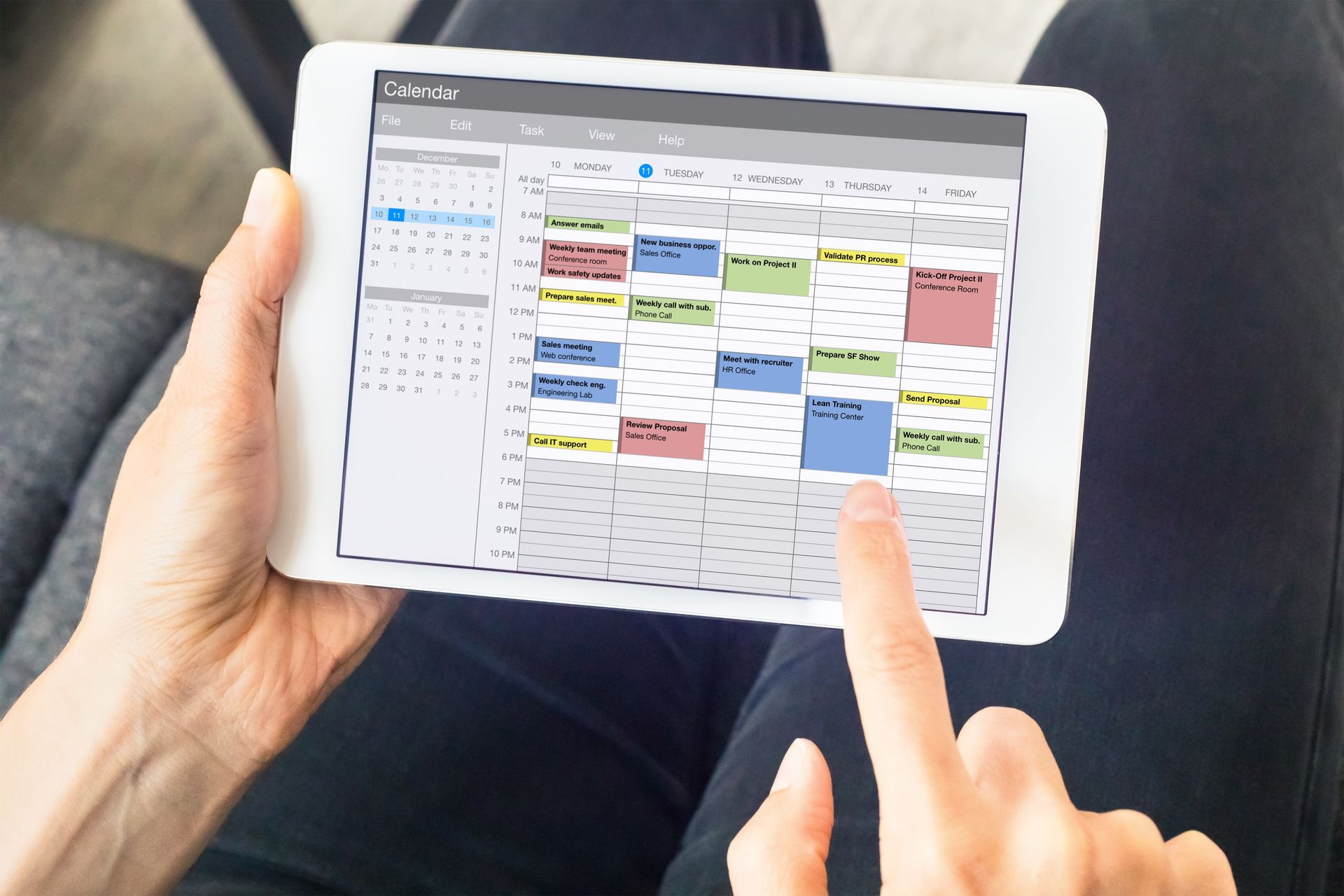 A person is holding a tablet with a calendar on it.