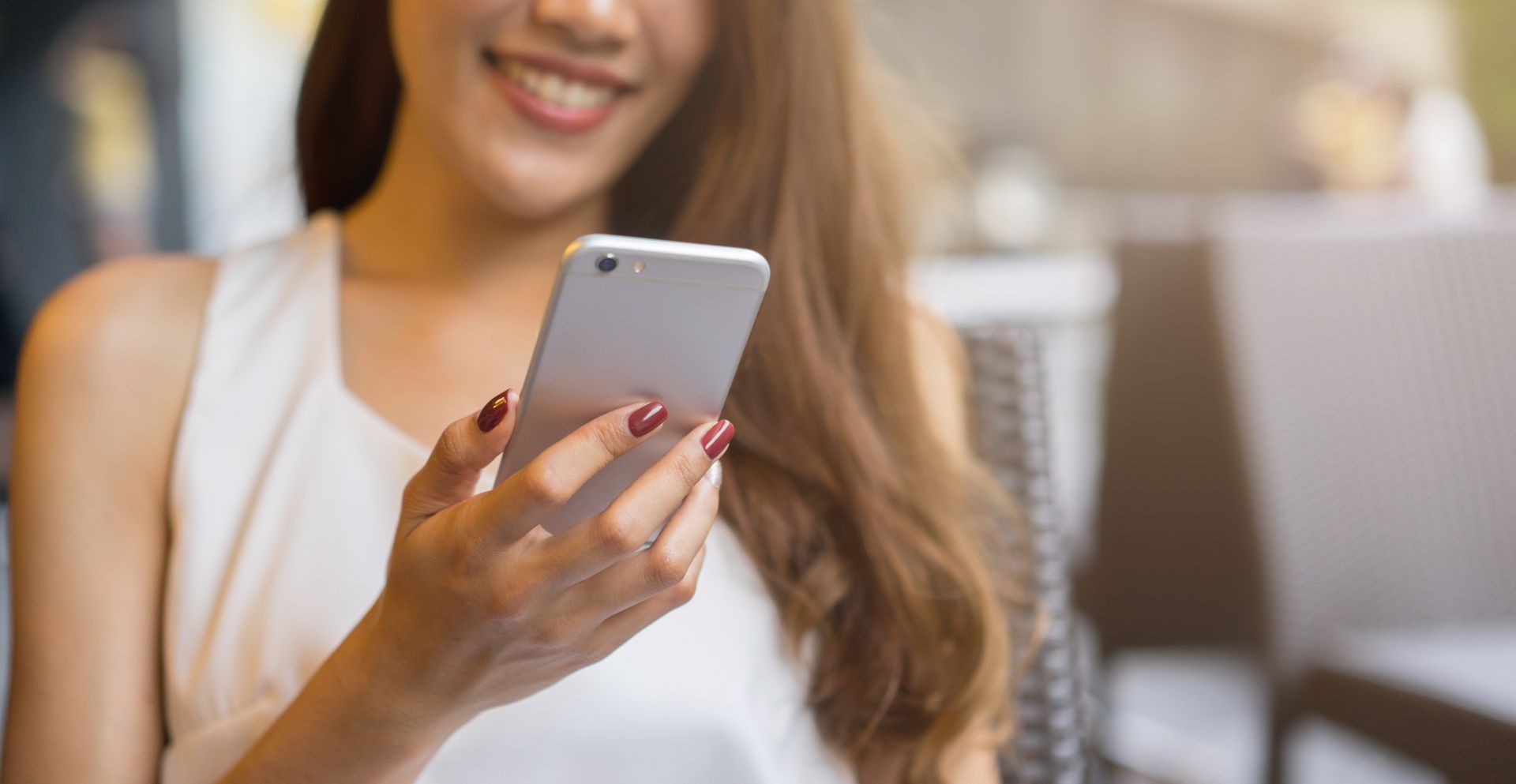 A woman is holding a cell phone in her hand and smiling.