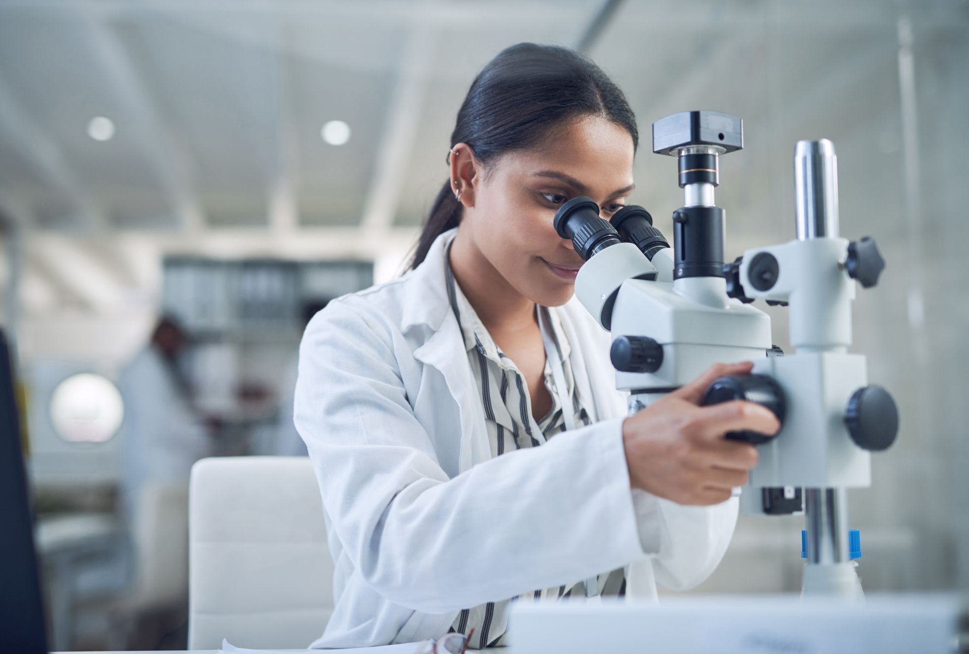 A female scientist is looking through a microscope in a laboratory.