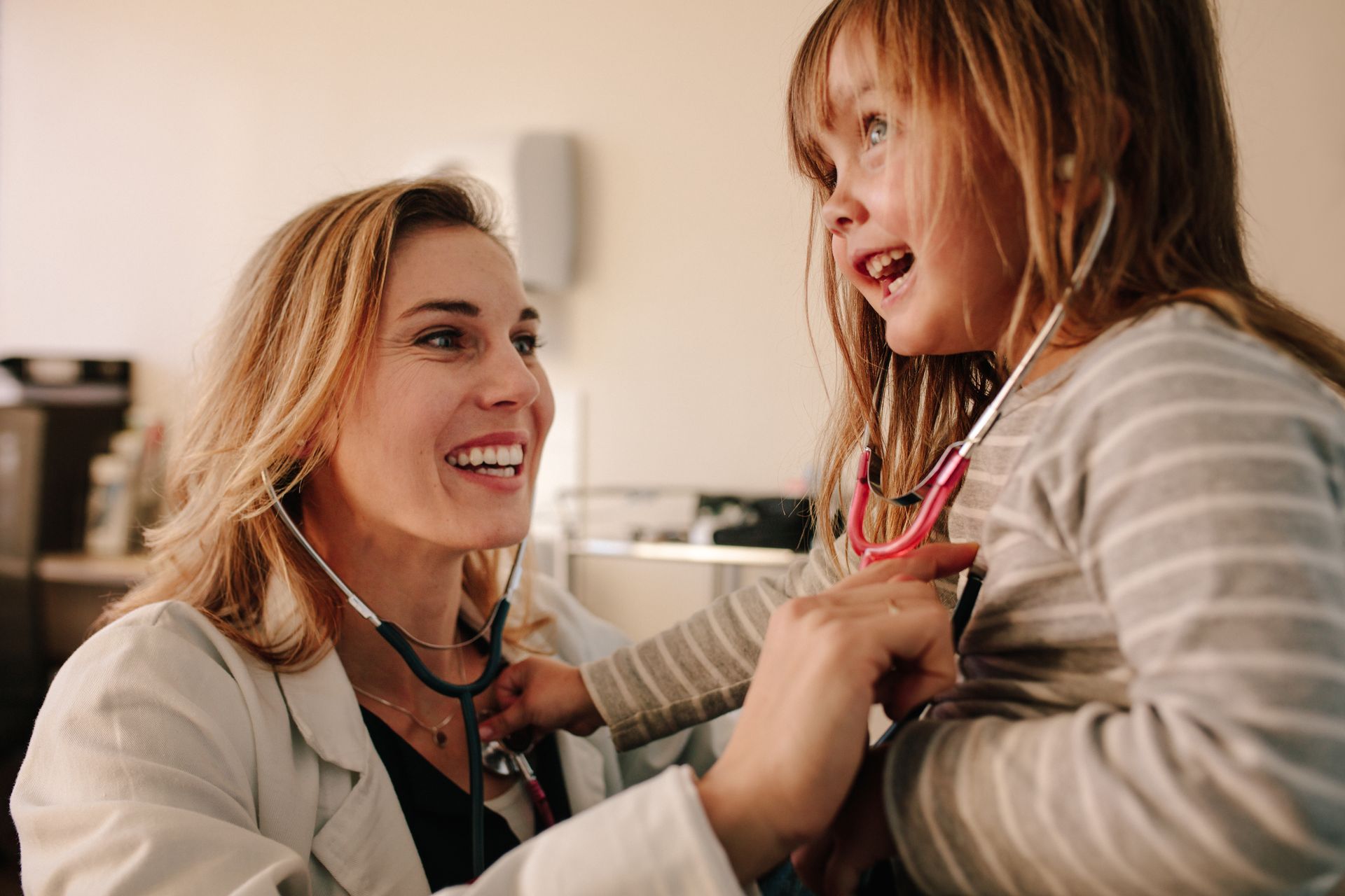 A doctor is listening to a little girl 's heart with a stethoscope.