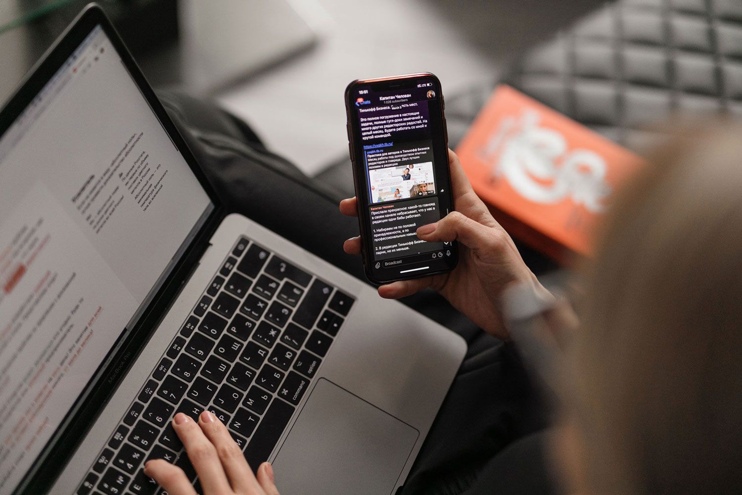 A person is using a laptop and a cell phone