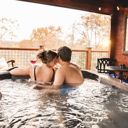 A man and a woman are sitting in a hot tub holding wine glasses.