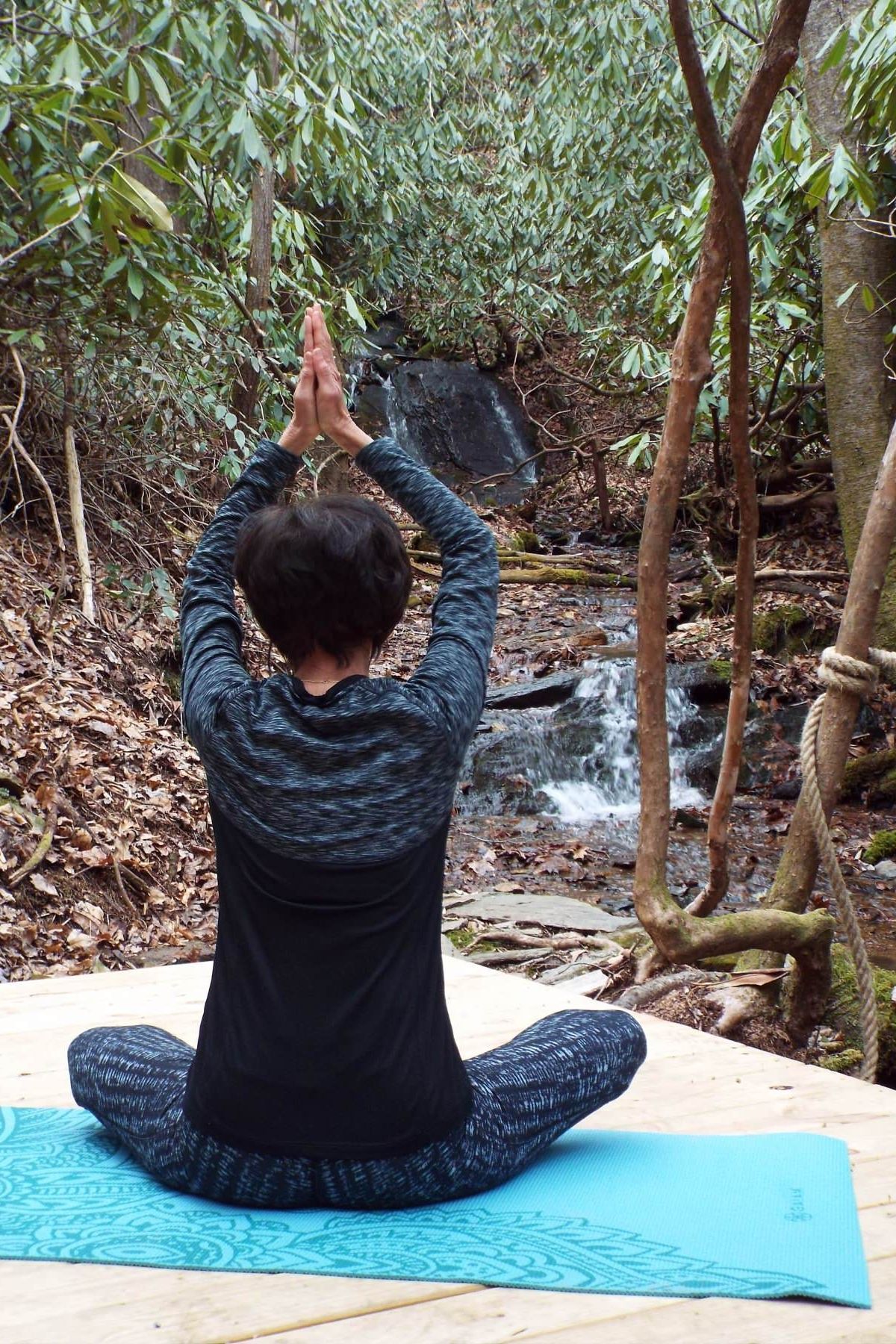 a woman is sitting on a yoga mat in front of a waterfall .