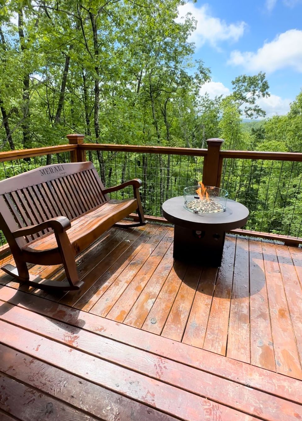 A wooden deck with a hot tub and a fire pit.