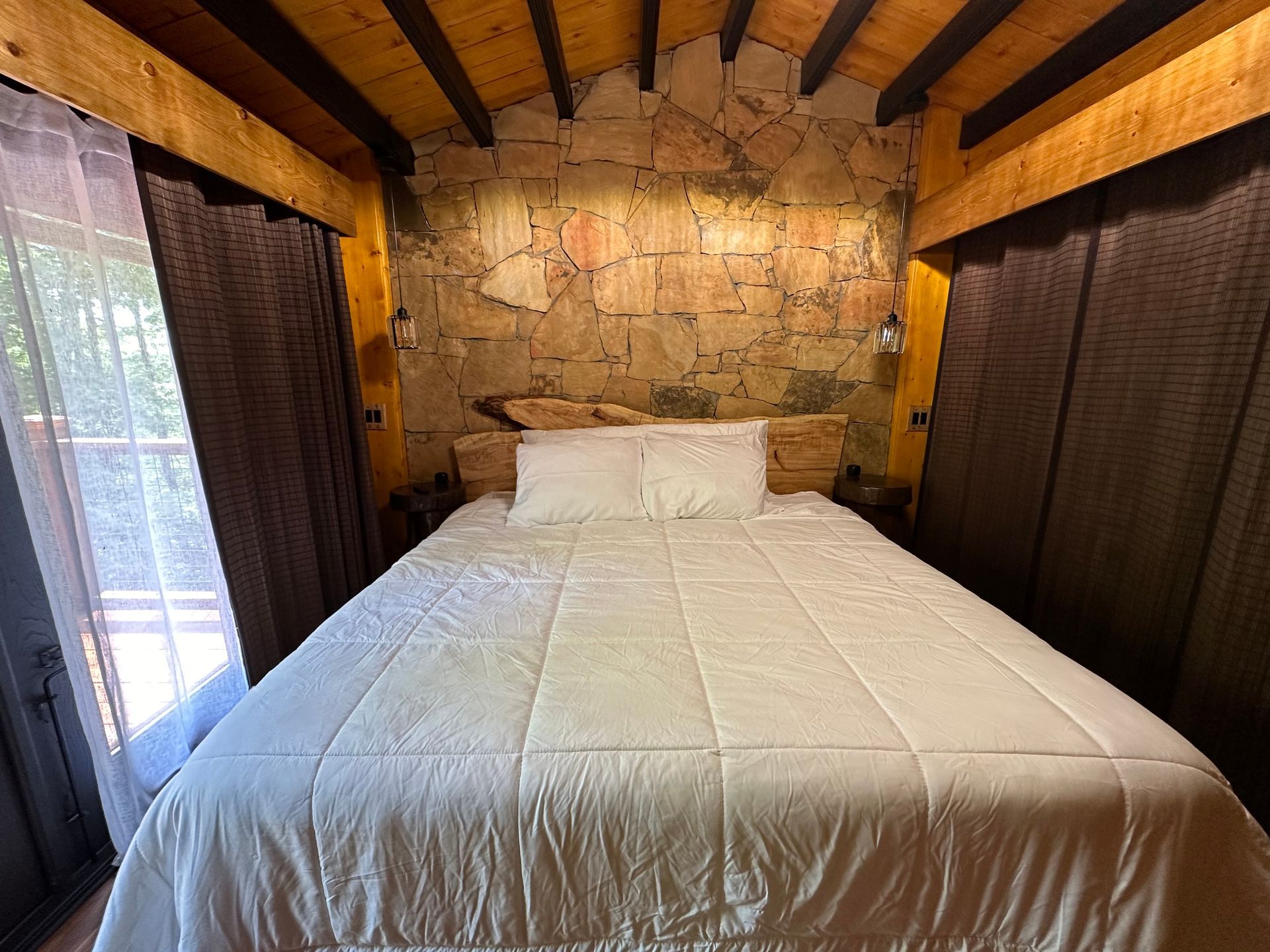 A bedroom with a large bed and a stone wall.