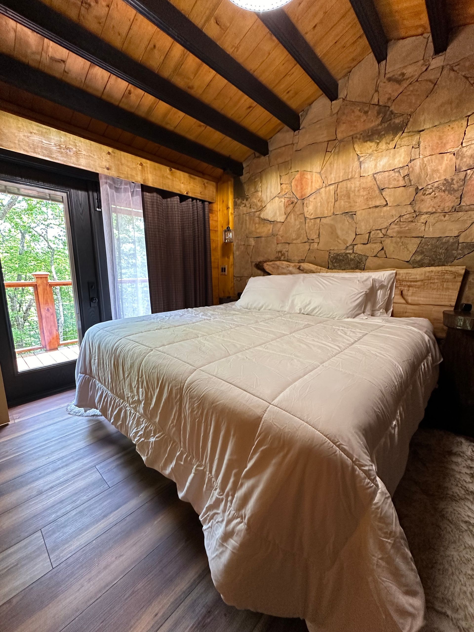 An empty room with a wooden floor and a stone wall
