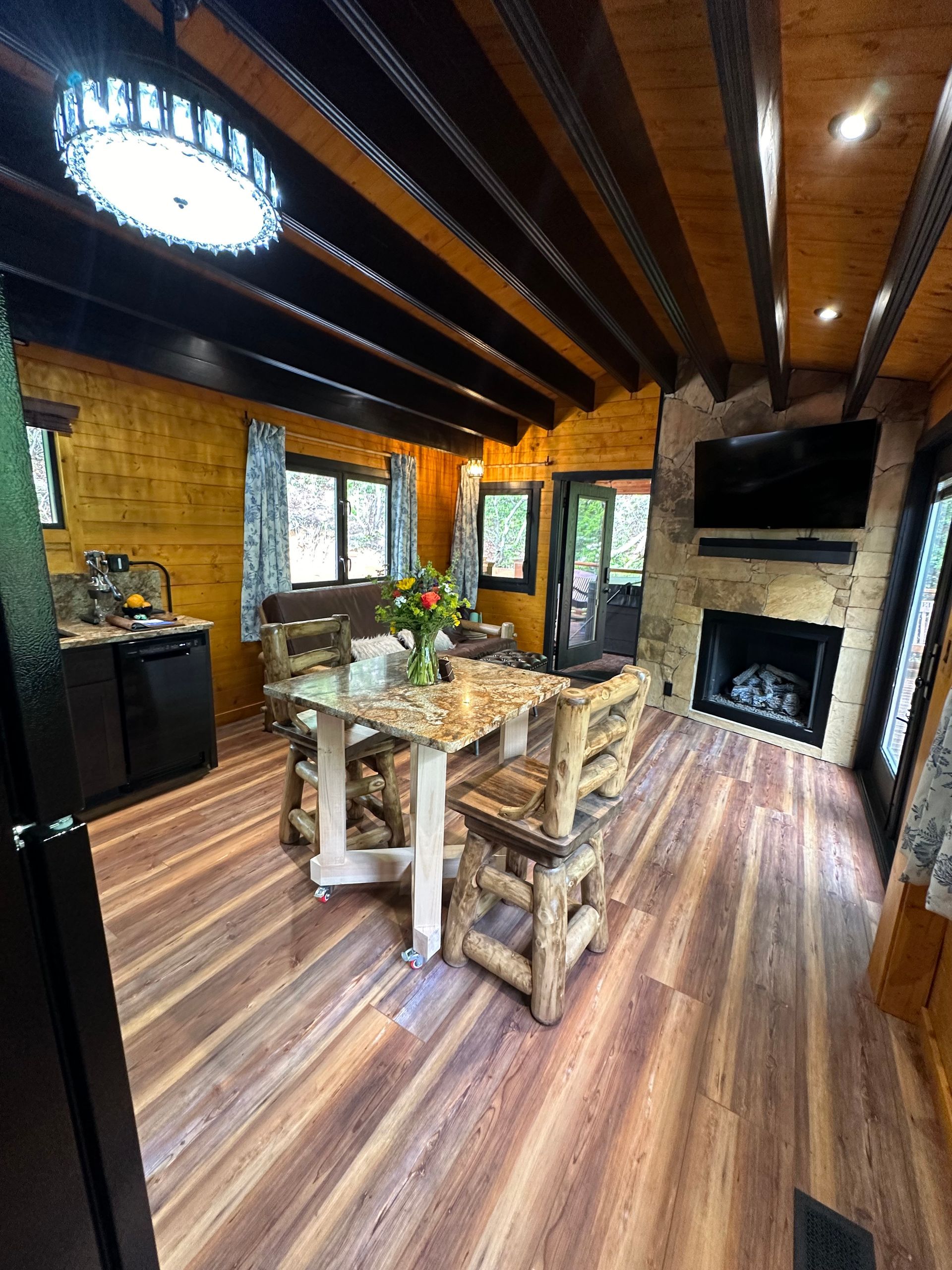 A living room in a log cabin with a couch and a kitchen.