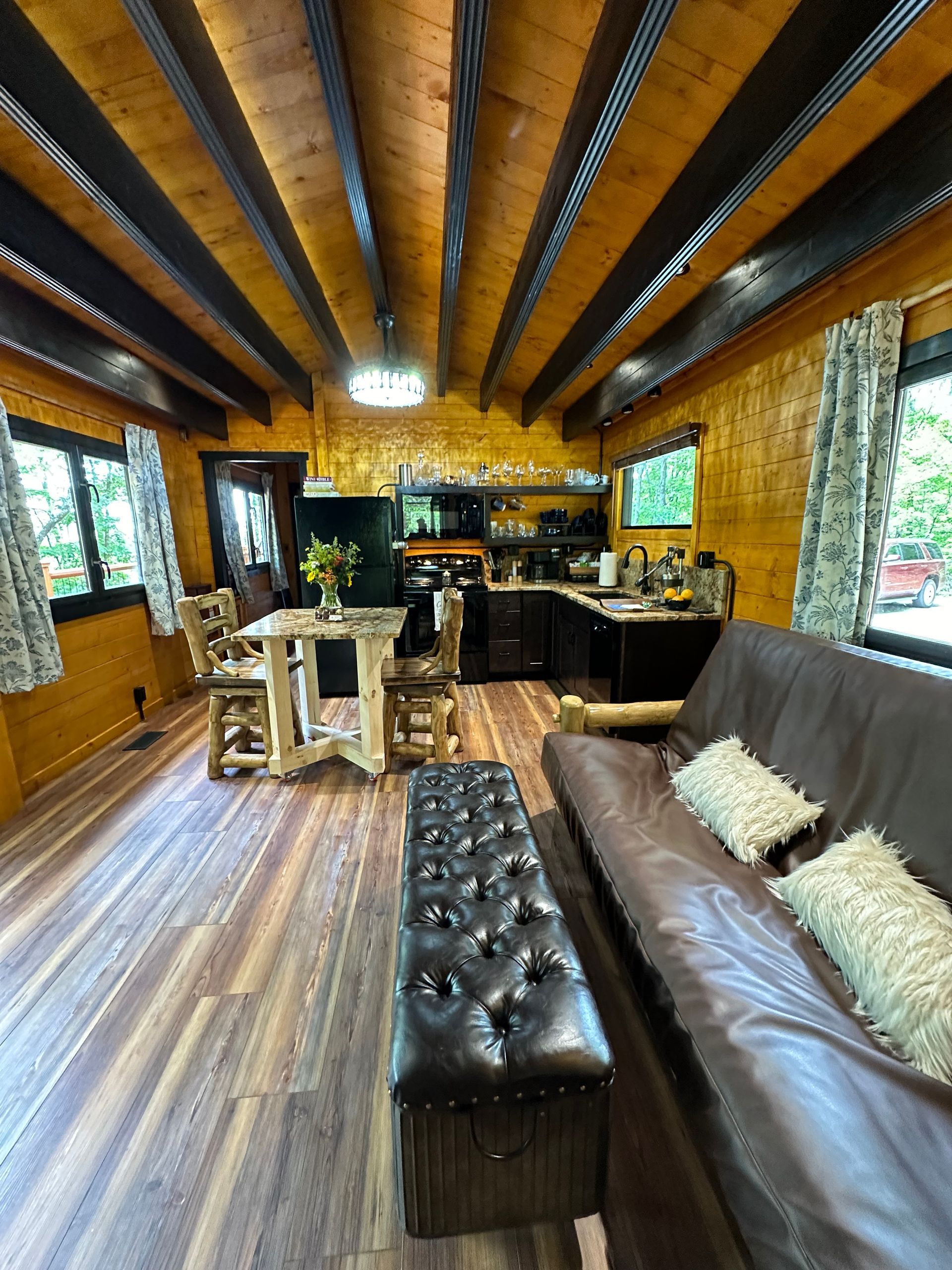 A living room with a couch , table and chairs in a log cabin.